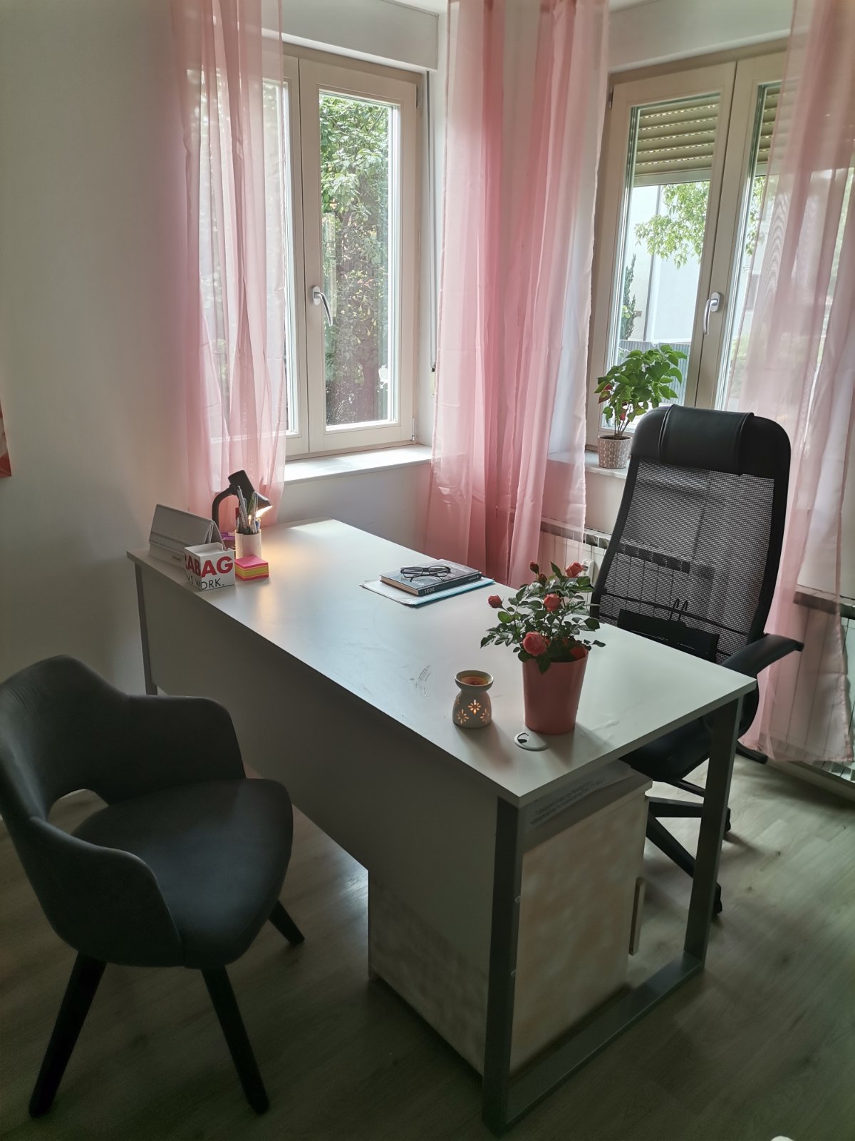 Svetel delovni prostor z mizo in rožnatimi zavesami